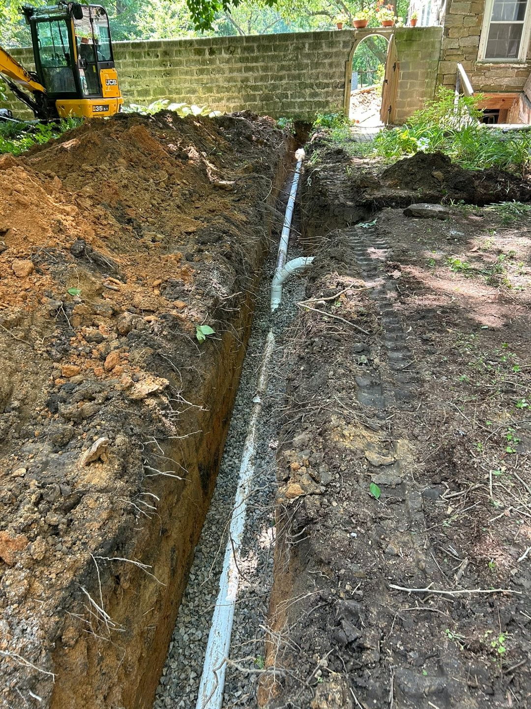 New sewer line installation with trench excavation, stone bedding, and PVC pipe placement