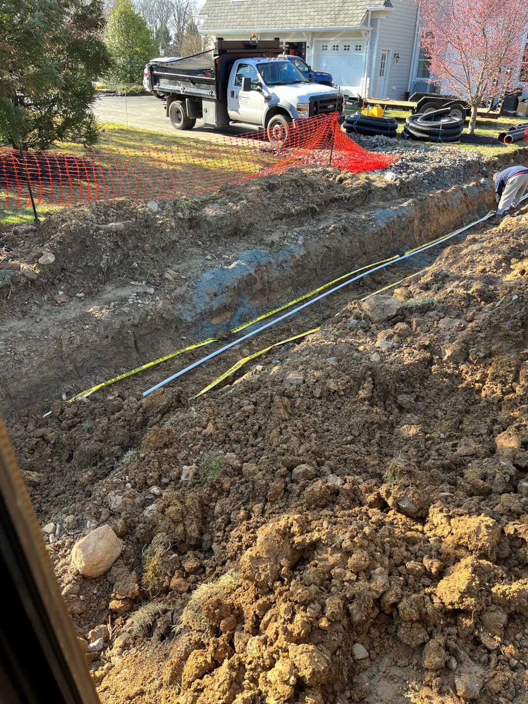 Underground utility trenching with safety fencing, pipe materials, and ES Excavation truck on site