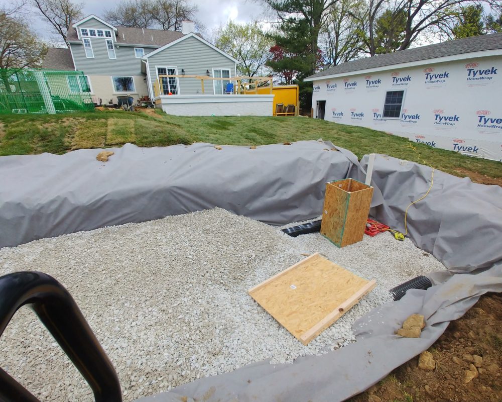 Backyard pool construction with gravel base and liner installation underway.